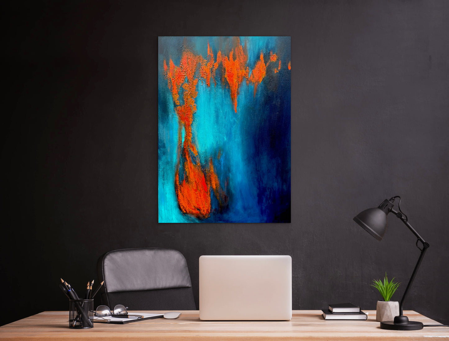 Abstract painting with orange and blue on a black wall above a desk.