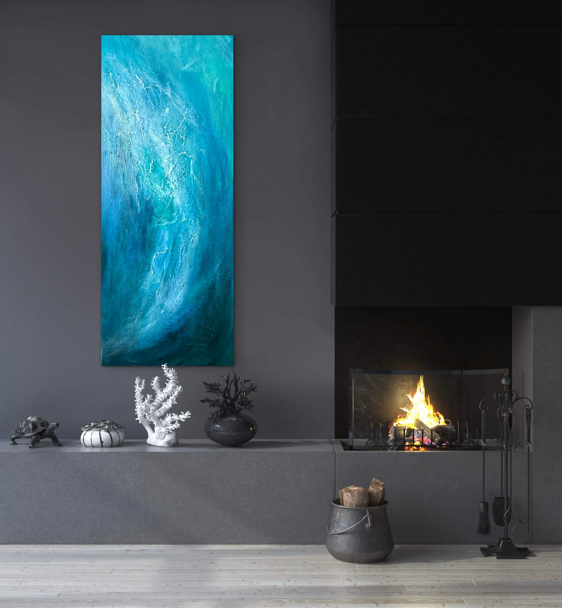 A tall vertical canvas print featuring an abstract blue and turquoise wave design, displayed on a dark gray wall above a modern fireplace mantel with decorative objects.