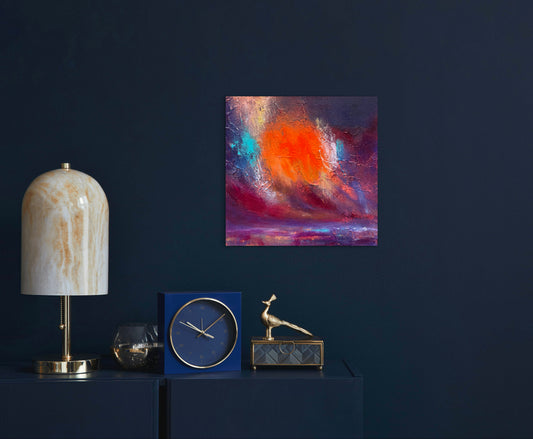 An abstract canvas painting with vibrant orange, red, purple, and blue brushstrokes, displayed on a dark navy wall above a console table styled with a marble lamp, blue clock, and gold decorative objects.